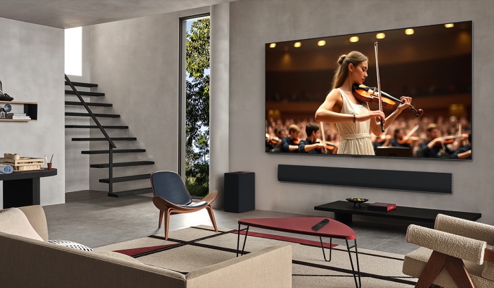 غرفة معيشة مع تلفزيون LG TV ومكبر الصوت LG Soundbar. يوجد على الشاشة حفل موسيقي. تظهر عازفة الكمان في الأمام، خلفها أوركسترا. تنبعث الدوائر متحدة المركز من التلفزيون الذي يوضح كيفية قيام ميزة AI Acoustic Tuning بفحص الغرفة وضبط الصوت وفقًا لمساحتك. 